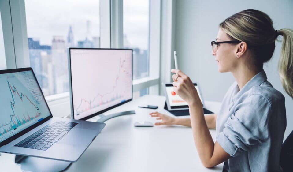 Female broker studying diagram on computer screen at work