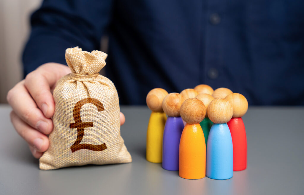 A businessman holds a british pound sterling money bag near a group of people figurines. Preferential loans for entrepreneurs and businesses. Social support. Allocation of budget money for projects.