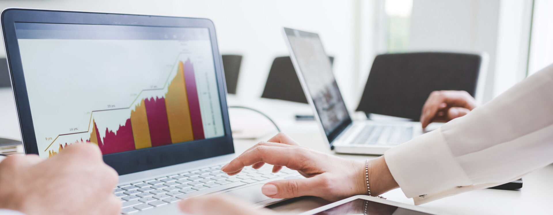 Cropped shot of businessmen and woman looking at laptop charts in office