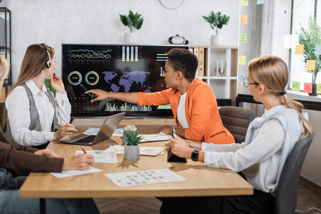 Group of diverse female colleagues looking at computer monitor with worldwide business concept