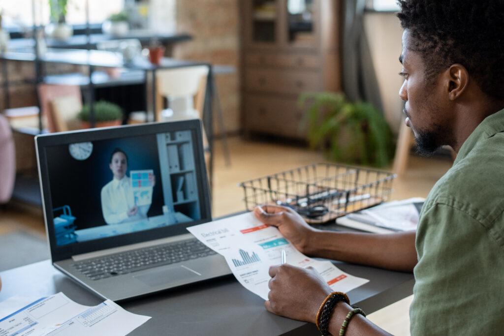 Young African man watching online video consultation of economist