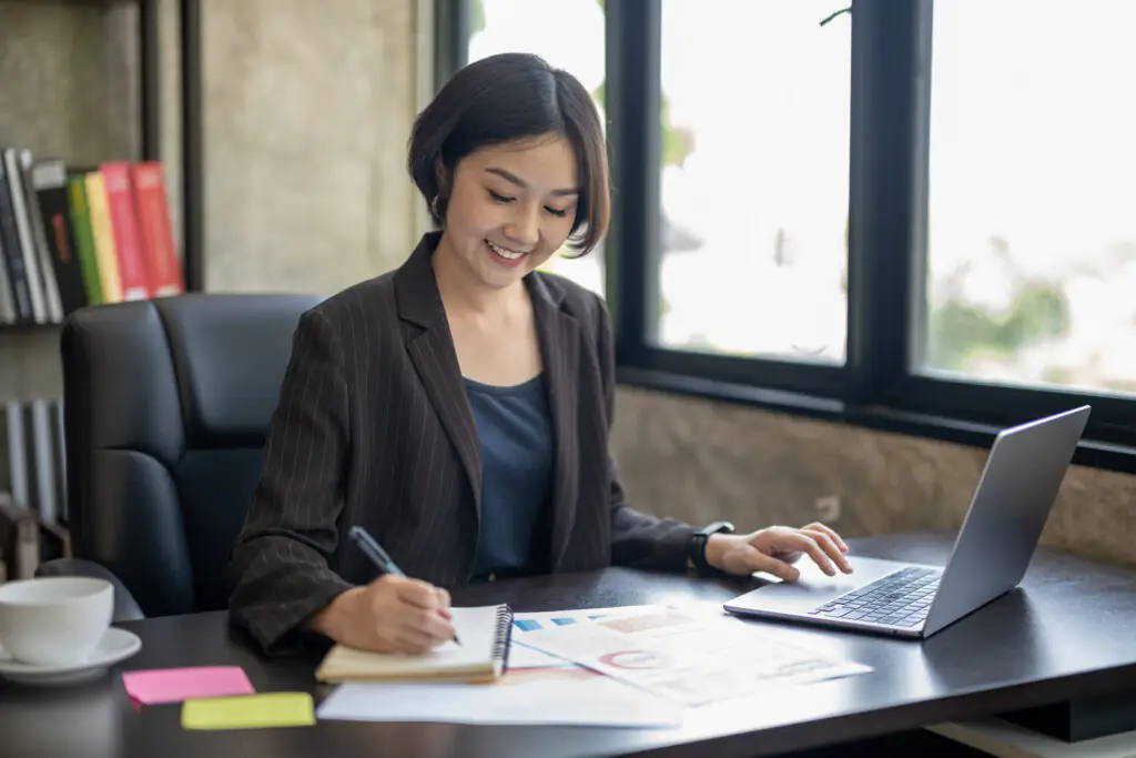 woman working on her online certificate writing notes