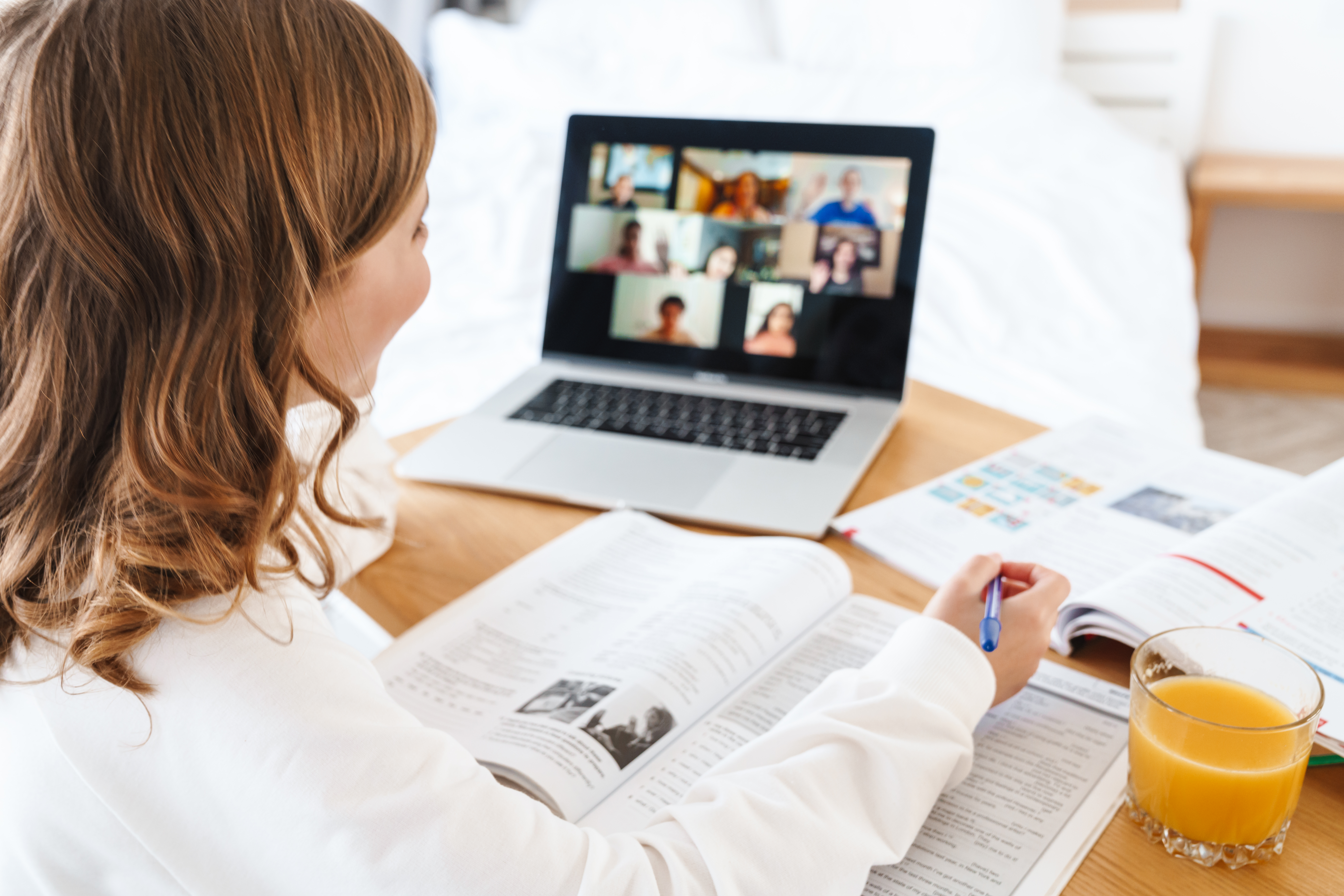 Photo of girl writing in exercise book while studying online
